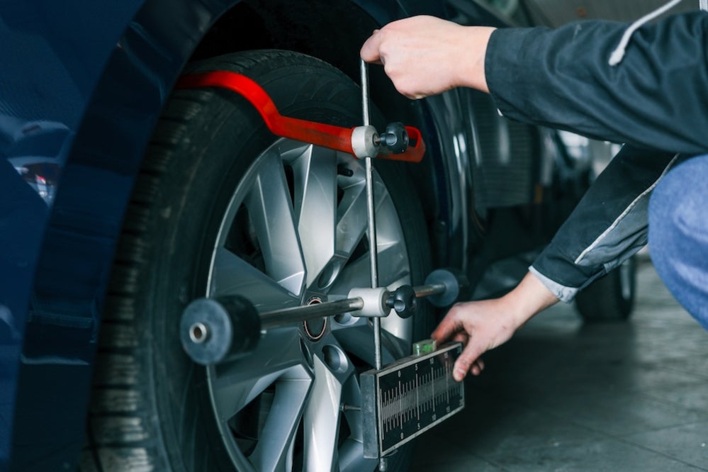 A mechanic adjusts a vehicle’s wheel alignment