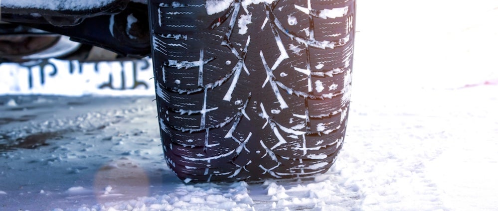 A closeup of the treads of a vehicle’s tire in the snow