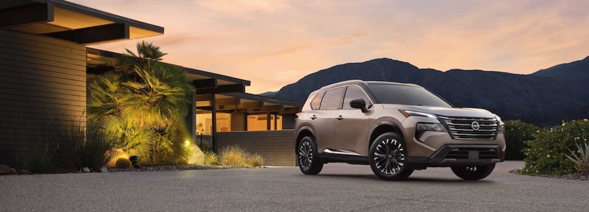 A gray 2026 Nissan Rogue SUV parked in front of a modern home at sunset