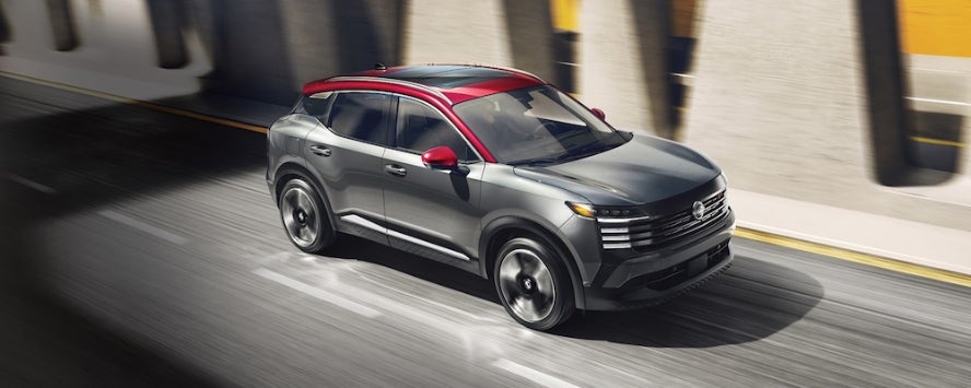 A two-tone gray and red 2026 Nissan Kicks SUV driving down the highway