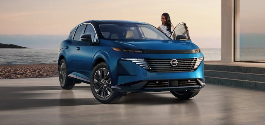 A woman getting into a blue 2026 Nissan Murano SUV parked by the beach