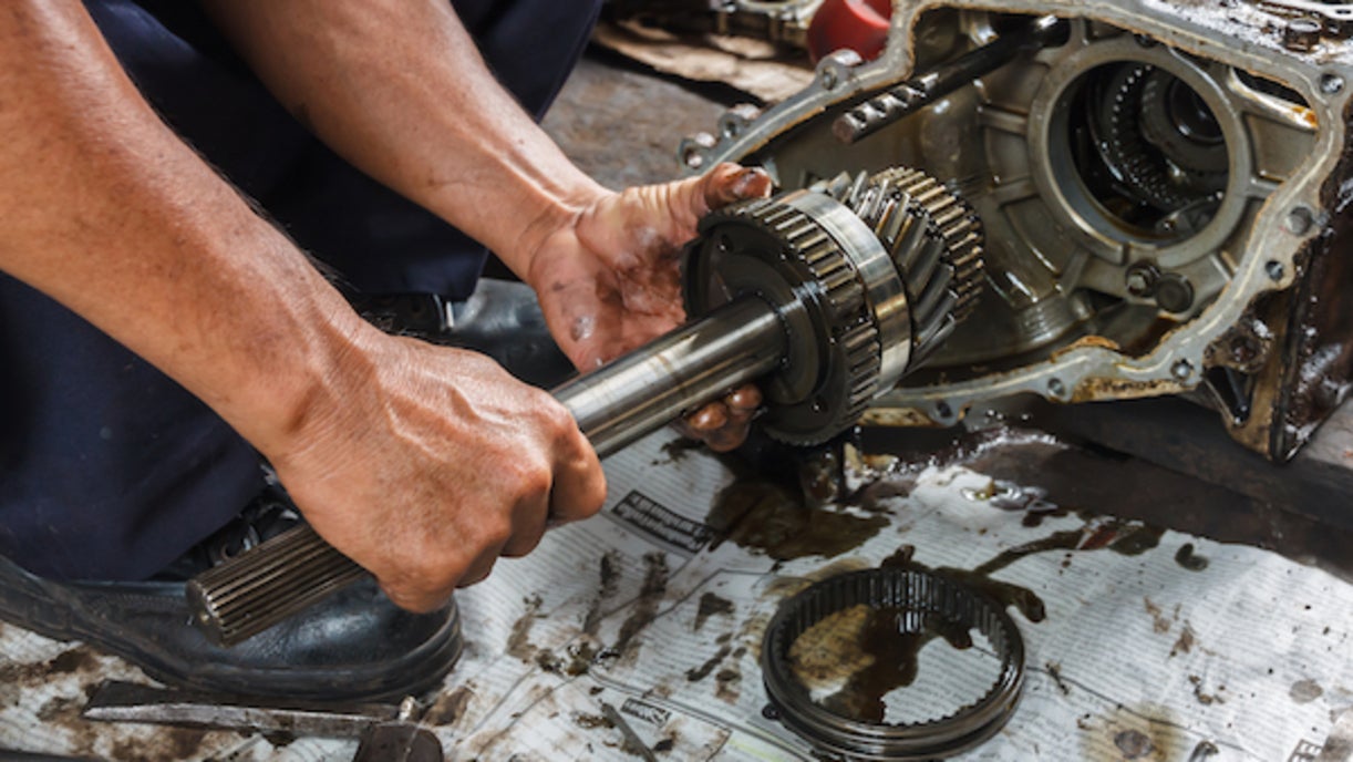 A person's hands gripping a vehicle's disassembled transmission