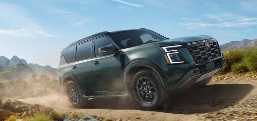 A dark green 2026 Nissan Armada driving down a dusty road