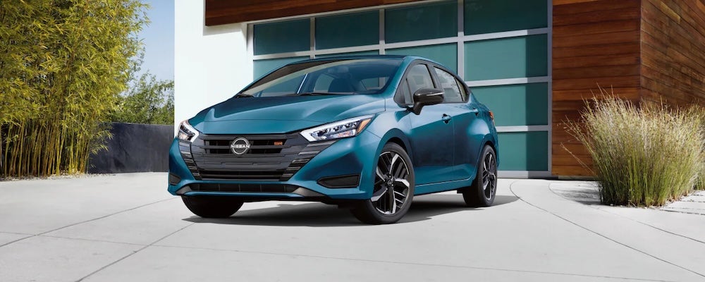 A blue 2025 Nissan Versa parked in a house's driveway