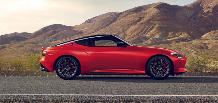 A red 2026 Nissan Z sports car parked on a road with mountains in the distance